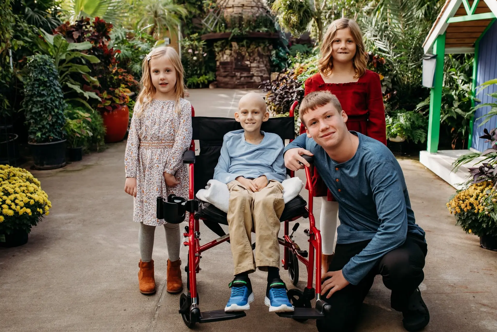Gavin in his wheelchair, smiling, with his brother and two of his sisters in a garden